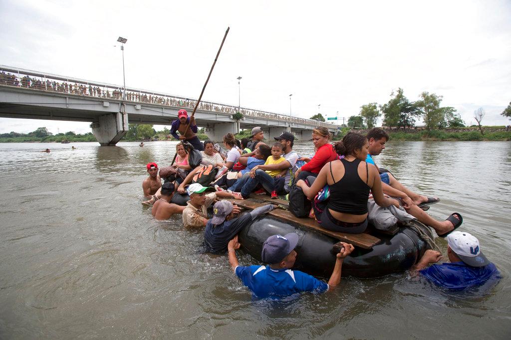 A group of Central American migrants cross the Suchiate River aboard a raft made out of tractor inner tubes and wooden planks, on the the border between Guatemala and Mexico, in Ciudad Hidalgo, Mexico, before illegally entering Mexico on Oct. 20, 2018. (AP Photo/Moises Castillo)