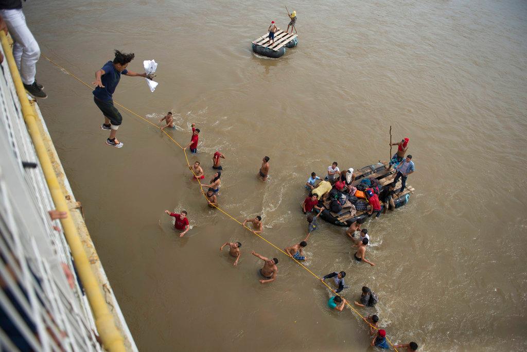Migrants tired of waiting to cross into Mexico, jumped from a border bridge into the Suchiate River, in Tecun Uman, Guatemala, Oct. 19, 2018. (AP Photo/Oliver de Ros)