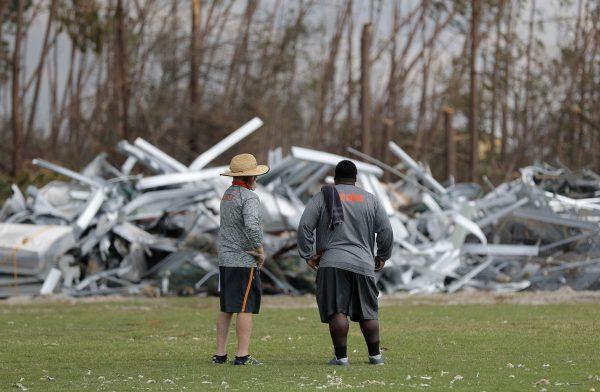Mosley High defensive coordinator Danny Nagy, left, and defensive line coach William Mosley, survey damage to their football practice field, in the aftermath of Hurricane Michael in Lynn Haven, Fla., Oct. 19, 2018. (AP Photo/Gerald Herbert)