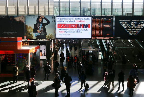 People walk past a "debt clock" screen, installed by Bruno Leoni Institute's analysts, displaying Italy's public debt at the Termini central station in Rome, Italy, on Feb. 15, 2018. (Alessandro Bianchi/Reuters)
