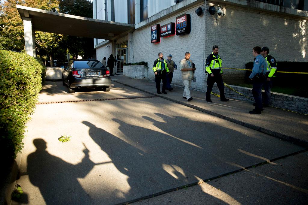 Shadows of reporters are behind police tape as police respond after a man was shot by a security guard while trying to break into the lobby of a building housing the offices of WTTG-TV, the local Fox broadcast affiliate in Washington, Monday, Oct. 22, 2018. (AP Photo/Andrew Harnik)