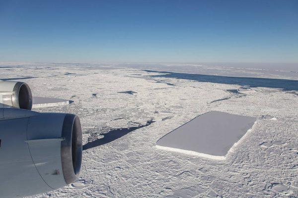 The A68 iceberg (center R), while the iceberg with highly regular features is in the background adjacent to the plane engine cowling. The image was captured by NASA in the Antarctic on Oct. 16, 2018. (Jeremy Harbeck/NASA)