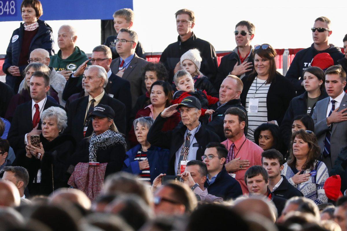 Attendees during the national anthem at a Make America Great Again rally in Mosinee, Wis., on Oct. 24, 2018. (Charlotte Cuthbertson/The Epoch Times)