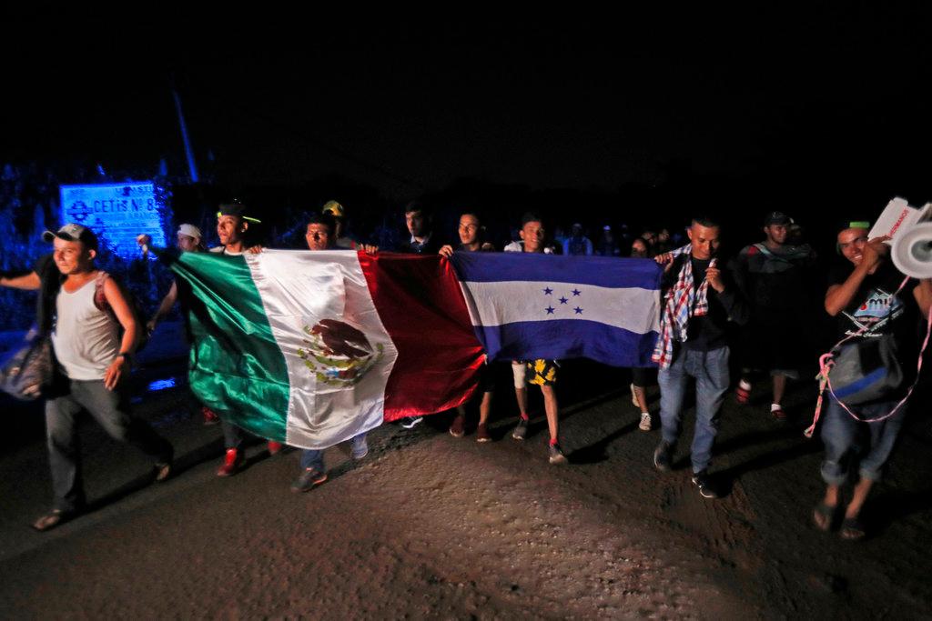 Central American migrants traveling with a caravan towards the United States walk holding national flags from Mexico and Honduras, as they make their way to Mapastepec, Mexico, on Oct. 24, 2018. (AP Photo/Moises Castillo)