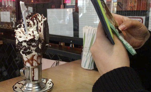 A millennial takes a photo of her Cookie 'n Cream Supreme Oreo shake at Black Tap in NYC (Ilene Eng/The Epoch Times)