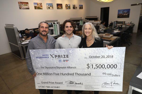 The Skysource/Skywater Alliance co-founders David Hertz, left, his wife Laura Doss-Hertz, right, and project designer Willem Swart pose for a photo with an image of a $1.5 million prize the company received in Los Angeles, on Oct. 24, 2018. (AP Photo/Marcio Jose Sanchez)