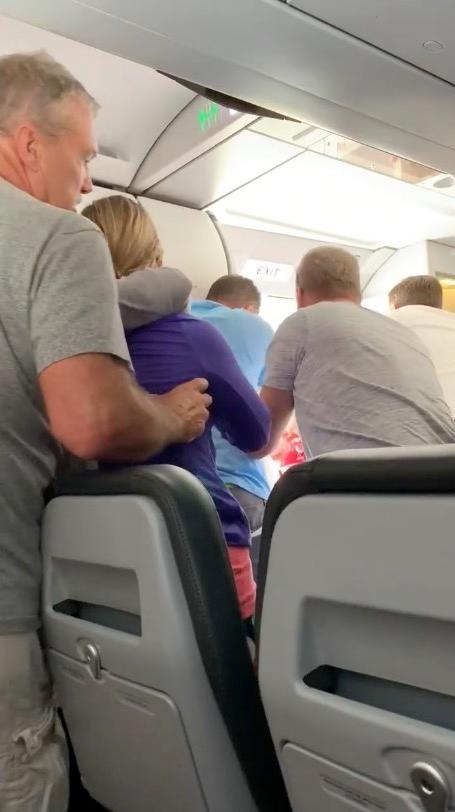 Passengers and crewmembers try to prevent the distressed passenger from leaping out of the moving aircraft, on Oct. 23, 2018. (Kathleen Ingham via Storyful)