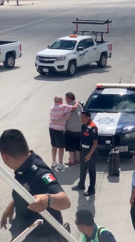 A man presumed to be the distressed passenger’s father consoles him after he forced open the aircraft door, prompting a police response, on Oct. 23, 2018. (Kathleen Ingham via Storyful)