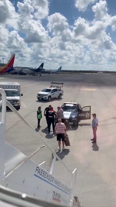 Police and airport officials talk to the distressed passenger, as an elderly man presumed to be a relative stands holding a suitcase, on Oct. 23, 2018. (Kathleen Ingham via Storyful)