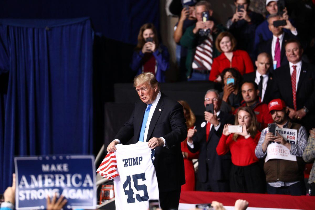 President Donald Trump holds a t-shirt passed up by an attendee at a Make America Great Again rally in Charlotte, N.C., on Oct. 26, 2018. (Charlotte Cuthbertson/The Epoch Times)