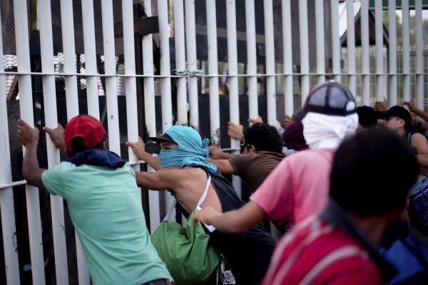 Central American migrants try to force their way through a customs gate at the border bridge connecting Guatemala and Mexico, in Tecun Uman, on Oct. 28, 2018. (Santiago Billy/AP)