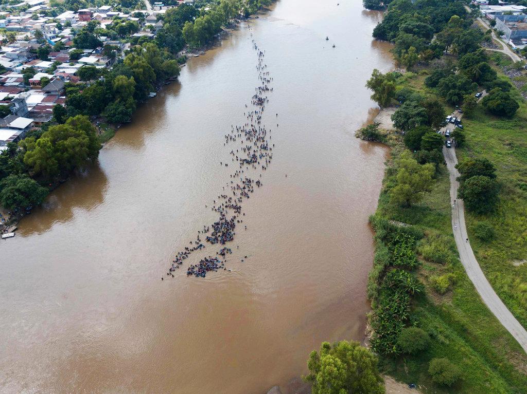A new group of Central American migrants bound for the U.S border wade in mass across the Suchiate River, that connects Guatemala and Mexico, in Tecun Uman, Guatemala on Oct. 29, 2018. The first migrant caravan group was able to cross the river on rafts—an option now blocked by Mexican Navy river and shore patrols. (AP Photo/Santiago Billy)