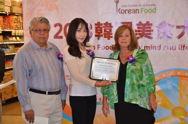 Milpitas Vice Mayor Marsha Grilli (R) and Milpitas councilmember Bob Nunez (L) present a commendation to Park Ji-hui, manager of the Los Angeles branch of aT, during the 2018 Korean Healthy Food Awards at 99 Ranch Market in Milpitas on Oct. 20, 2018.  (David Zhang/The Epoch Times)