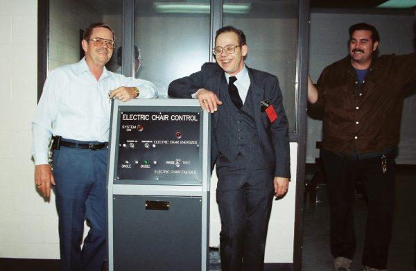 In this undated photo released by Fred Leuchter, center, he stands near the control panel for the electric chair he built. (Courtesy of Fred Leuchter via AP)