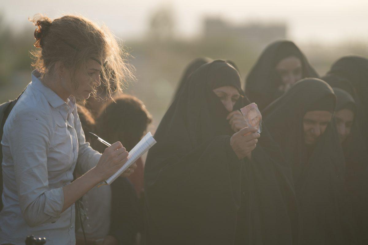 Marie Colvin (Rosamund Pike, L) discovers a mass grave outside of Fallujah, Iraq, and bears witness as backhoes dig up skeletons, in “A Private War.” (Keith Bernstein/Aviron Pictures)
