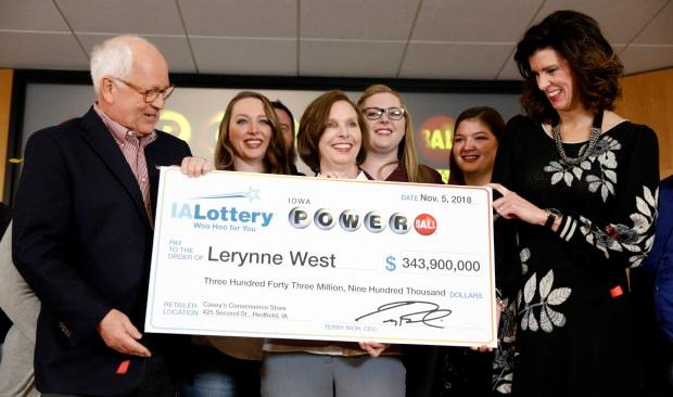 Iowa Lottery CEO Terry Rich, left, presents a check to Lerynne West, of Redfield, Iowa, center, for her share of a nearly $700 million Powerball prize, Monday, Nov. 5, 2018, at the Iowa Lottery headquarters in Clive, Iowa. (AP Photo/Charlie Neibergall)