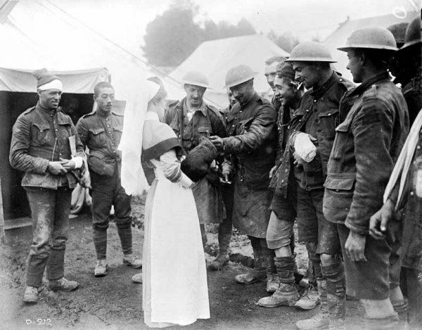 A nursing sister is presented with a dog by injured Canadian soldiers at a Casualty Clearing Station, October 1916. (Library and Archives Canada)