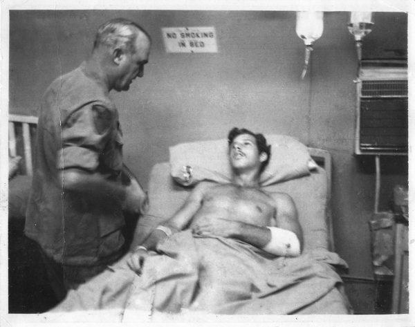 Commanding Gen. George Putnam stops by Randy Clifford’s hospital bed in Vietnam on March 28, 1971, the day after Clifford was shot with an AK-47 while patrolling in a helicopter at low altitude. Putnam has pinned a Purple Heart medal to Clifford’s pillow. (Photo Courtesy of Randy Clifford)