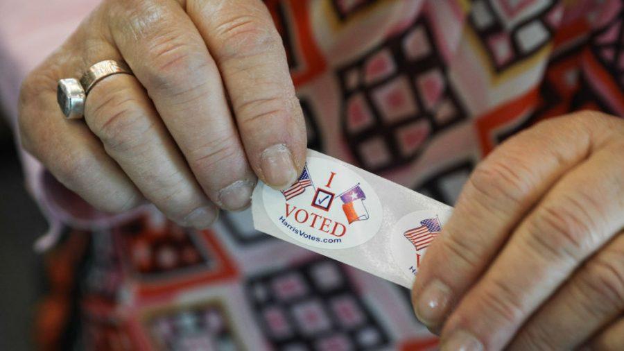 A woman in Texas hands out "I voted" stickers to voters at the Rummel Creek Elementary polling place in Houston on Nov. 6, 2018. (Loren Elliott/Getty Images)