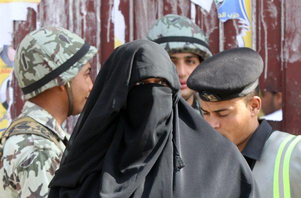 A burqa-clad Egyptian woman walks past soldiers as she leaves a polling station in Cairo on Jan. 29, 2012. (Khaled Desouka/AFP/Getty Images)