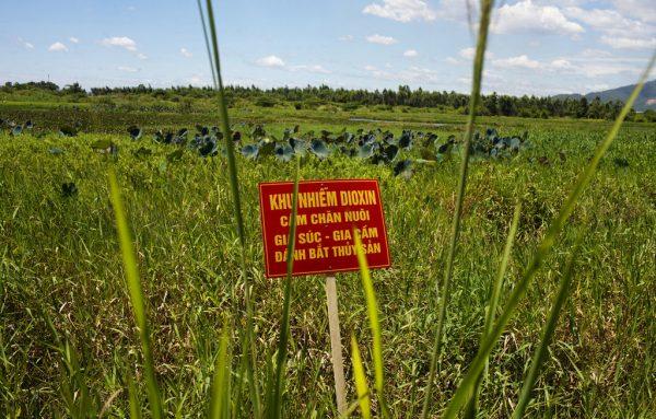 A warning sign stands in a field contaminated with dioxin near Da Nang airport in Vietnam. The sign reads; "Dioxin contamination zone—livestock, poultry, and fishery operations not permitted." (Maika Elan/AP Photo)