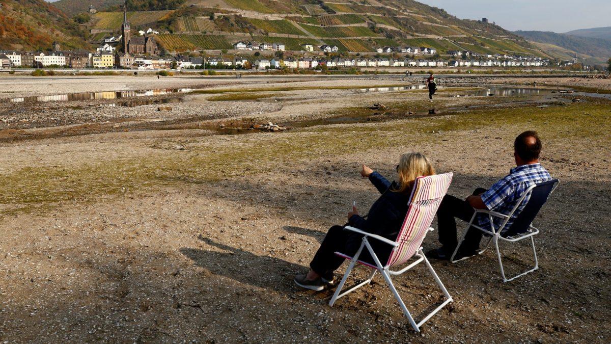 A couple sit on their camping chairs and look at Lorchhausen amid the river bed of the dried out Rhine, as water levels reached a historic low level and freight vessels cannot sail fully loaded on Europe's most important waterways, near Bacharach, Germany, on Oct. 19, 2018. (Wolfgang Rattay/Reuters)