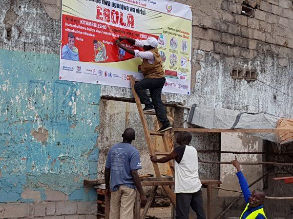 Workers fix an Ebola awareness poster in Tchomia, Democratic Republic of Congo, to raise awareness about Ebola in the local community, on Oct. 9, 2018. (Aboulaye Cisse/Reuters)