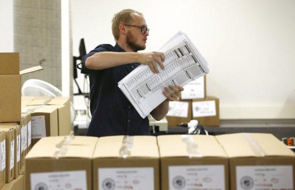 A worker carries ballots to be verified at the Maricopa County Recorder's Office in Phoenix, Arizona on Nov. 8, 2018. (AP Photo/Ross D. Franklin)