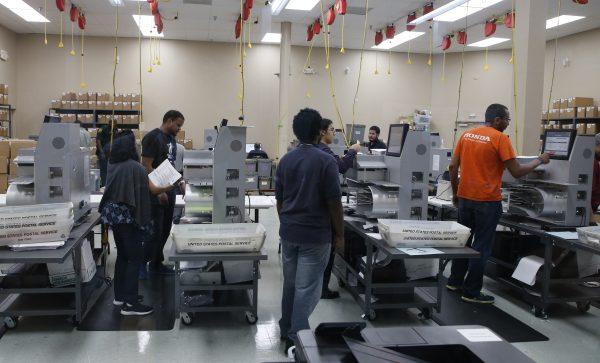 Elections workers feed ballots into tabulation machines at the Broward County Supervisor of Elections office in Lauderhill, Fla., on Nov. 10, 2018. (Joe Skipper/Getty Images)