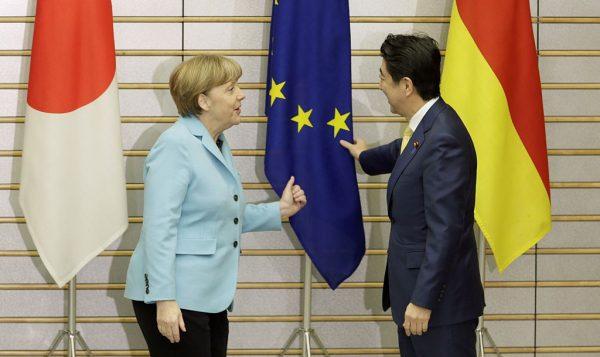 German Chancellor Angela Merkel and Japanese Prime Minister Shinzo Abe (R) talk about an EU flag at the start of talks at the latter's official residence in Tokyo on March 9, 2015. (Kimimasa Mayama/AFP/Getty Images)