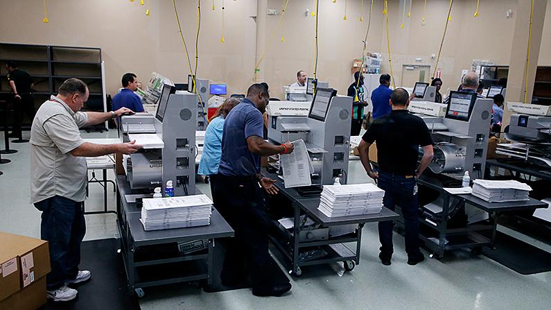 Elections staff load ballots into machines as recounting begins at the Broward County Supervisor of Elections Office in Lauderhill, Florida on Nov. 11, 2018. (Joe Skipper/Getty Images)