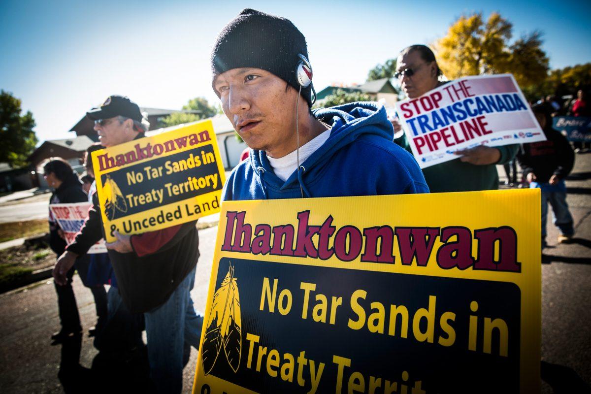 A man holding a sign bearing the name of the Ihanktonwan Indian tribe participates in a protest against the proposed Keystone XL pipeline in Pierre, South Dakota on Oct. 13, 2014. (Andrew Burton/Getty Images)