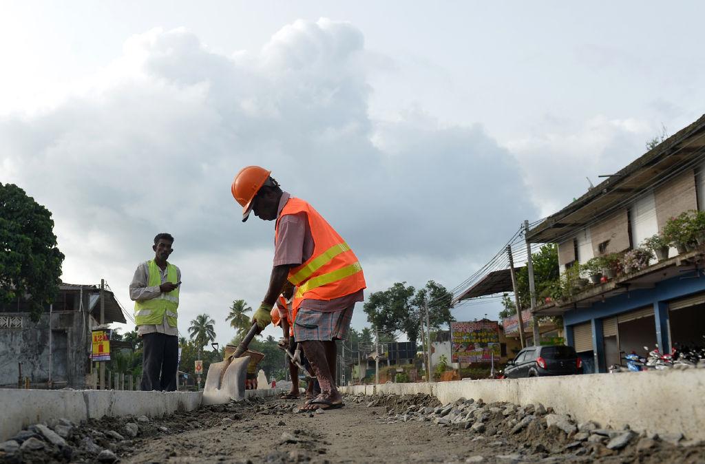 Sri Lankan road construction workers construction labourers work along a road in Colombo on Aug. 5, 2018. Sri Lanka's central bank on Aug. 3 announced it had secured a $1 billion Chinese loan as the island, a key link in Beijing's ambitious Belt and Road initiative, develops closer relations with Asia's largest economy. (Lakruwan Wanniarachchi/AFP/Getty Images)