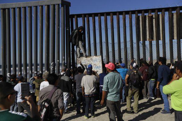 Central American migrants look on along the border structure, in Tijuana, Mexico on Nov. 14, 2018. (AP Photo/Gregory Bull)