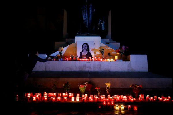 An activist places candles and flowers on the Great Siege monument, after rebuilding a makeshift memorial to assassinated anti-corruption journalist Daphne Caruana Galizia, during a vigil and protest to mark thirteen months since her murder, in Valletta, Malta, on November 16, 2018. (Darrin Zammit Lupi/Reuters)