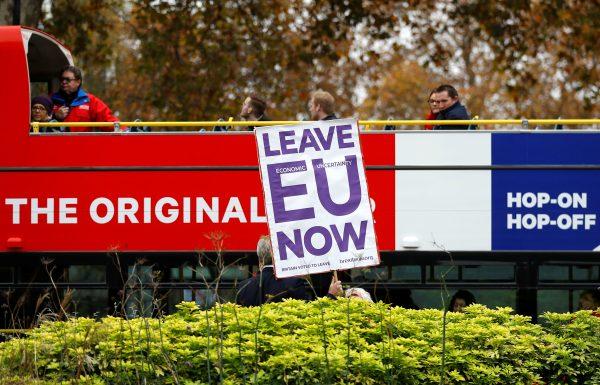 A pro-Brexit campaigner holds a placard as a tourist bus passes by in Westminster, London, on Nov. 16, 2018. (Reuters/Peter Nicholls)