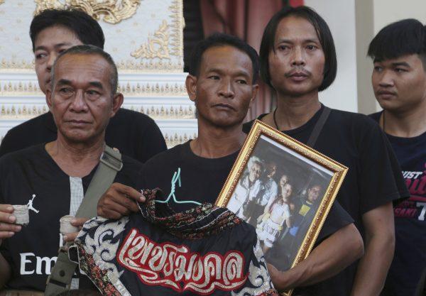 Relatives of 13-year-old Thai kickboxer Anucha Tasako hold his boxing shorts and a portrait during his funeral services in Samut Prakan province, Thailand, on Nov. 15, 2018. (Sakchai Lalit/AP)