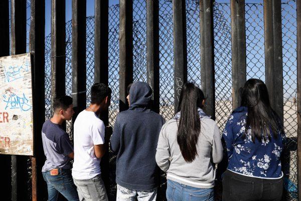 People look into the United States at the U.S.-Mexico border fence at Playas de Tijuana, Mexico, on Nov. 16, 2018. (Charlotte Cuthbertson/The Epoch Times)