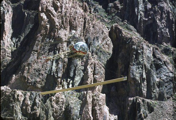 A Bell 47B helicopter transporting pipe sections from Yaki Point staging area to inner-canyon work site. Circa 1965. (NPS)