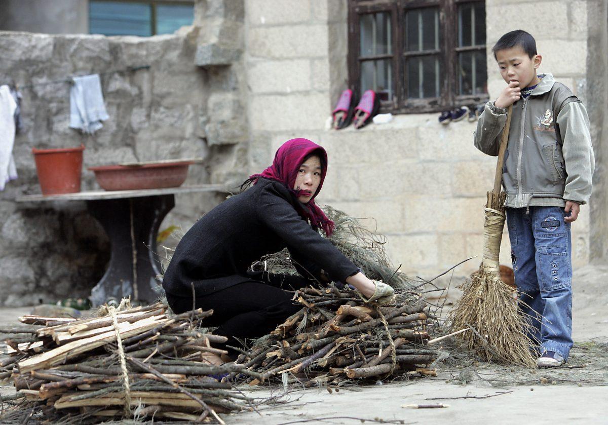 A  farmer ties a bunch of firewood as her son watches outside their home in Hutou village on Pingtan island, China, in this undated photo. (Goh Chai Hin/AFP/Getty Images)