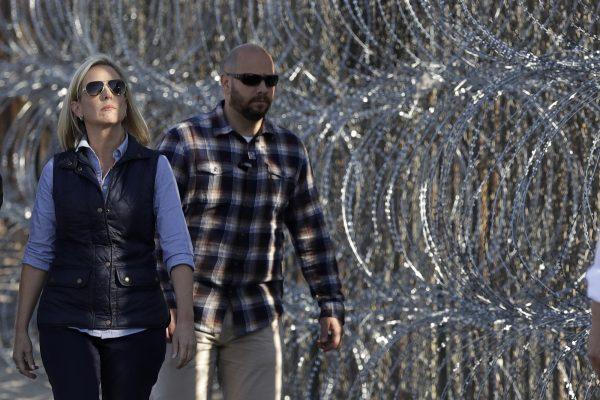 Secretary of Homeland Security Kirstjen Nielsen (L), walks next to a section of the border wall fortified with razor wire separating Tijuana, Mexico, and San Diego, on Nov. 20, 2018. (Gregory Bull/AP Photo)