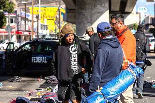 Marco Gómez (L) and several other Honduran migrants slept under a bridge across the road from the Chaparral port of entry to the United States in Tijuana, Mexico, on Nov. 23, 2018. (Charlotte Cuthbertson/The Epoch Times)