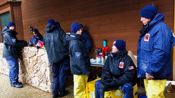 National Urban Search & Rescue Response System Orange County CATF-5 team members Imelda Cordova, third from right, talks to Andrew Ricker and Chris Stevens, far right, as their team takes cover from the rain in Paradise, Calif., on Nov. 23, 2018. (Kathleen Ronayne/AP)