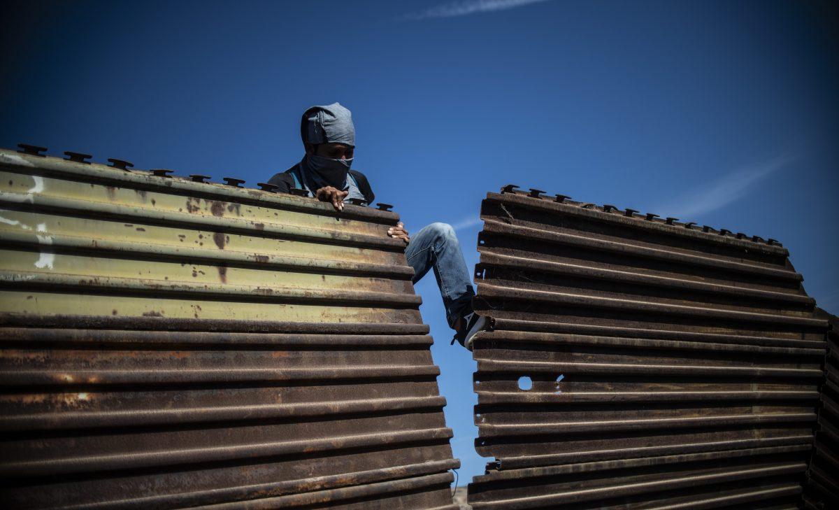 A Central American migrant tries to bring down part of the border fence between Mexico and the United States, near El Chaparral border crossing, in Tijuana, Baja California State, Mexico, on Nov 25, 2018. (Pedro Pardo/AFP/Getty Images)