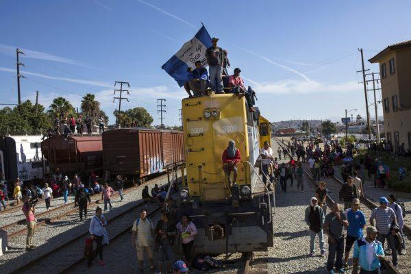 A migrant waves a Honduran flag along the railroad tracks at the Mexico-U.S. border in Tijuana, Mexico, Nov. 25, 2018, as a group of migrants tries to reach the United States. (Rodrigo Abd/AP Photo)