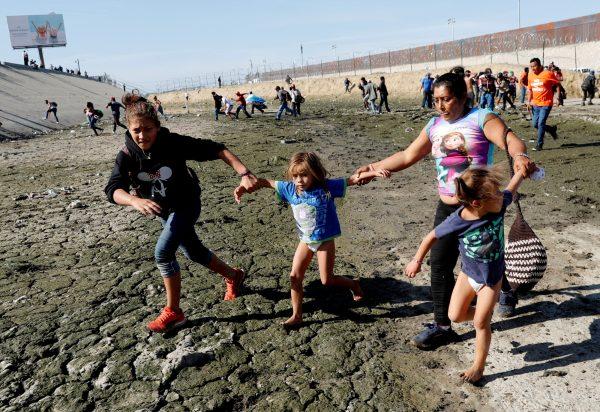 Maria Meza (2nd R), runs away from tear gas with her daughters Jamie Jisel Mejia Meza, aged 13 and her 5-year-old twin daughters Saira Nalleli Mejia Meza and Cheili Nalleli Mejia Meza (L-R) in front of the border wall between the U.S. and Mexico, in Tijuana, Mexico, Nov. 25, 2018. (Kim Kyung-Hoon/Reuters)