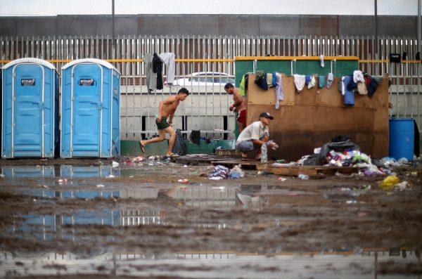 Migrants, part of a caravan of thousands from Central America trying to reach the United States, shower in front of the border wall with the United States, whilst they rest in a temporary shelter in Tijuana, Mexico, Nov. 28, 2018. (Hannah McKay/Reuters)