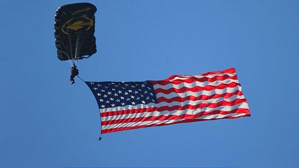 A file photo of a member of the U.S. Army Jump Team displaying the flag while descending over Sebring International Speedway in Florida before a race. (Chris Jasurek/The Epoch Times)
