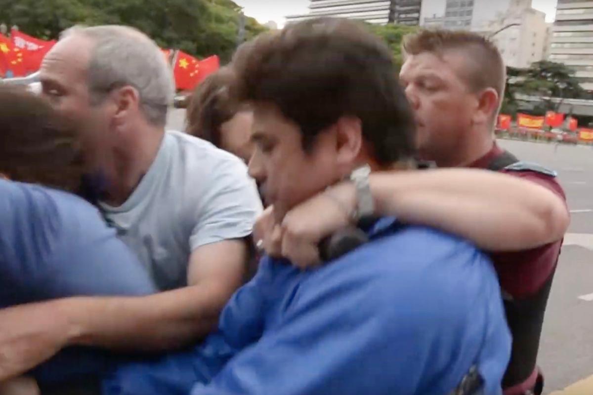 A police officer puts a male Falun Gong practitioner in a chokehold. (Screenshot via YouTube)
