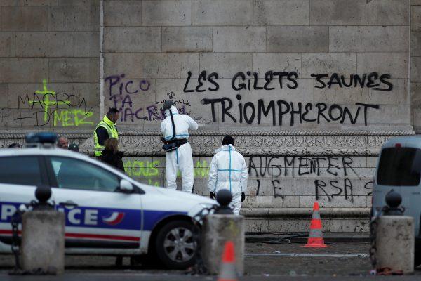 Police work around the message, "The Yellow Vests will Triumph" written on the Arc de Triomphe, the morning after clashes with protesters wearing yellow vests, a symbol of a French drivers' protest against higher diesel taxes, in Paris, on Dec. 2, 2018. (Benoit Tessier/Reuters)